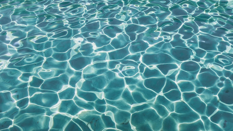Sunlight scattering across the rippled surface of a swimming pool.