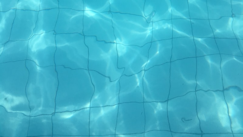 Clear pool water above a tiled floor, with the waterline tile visible.