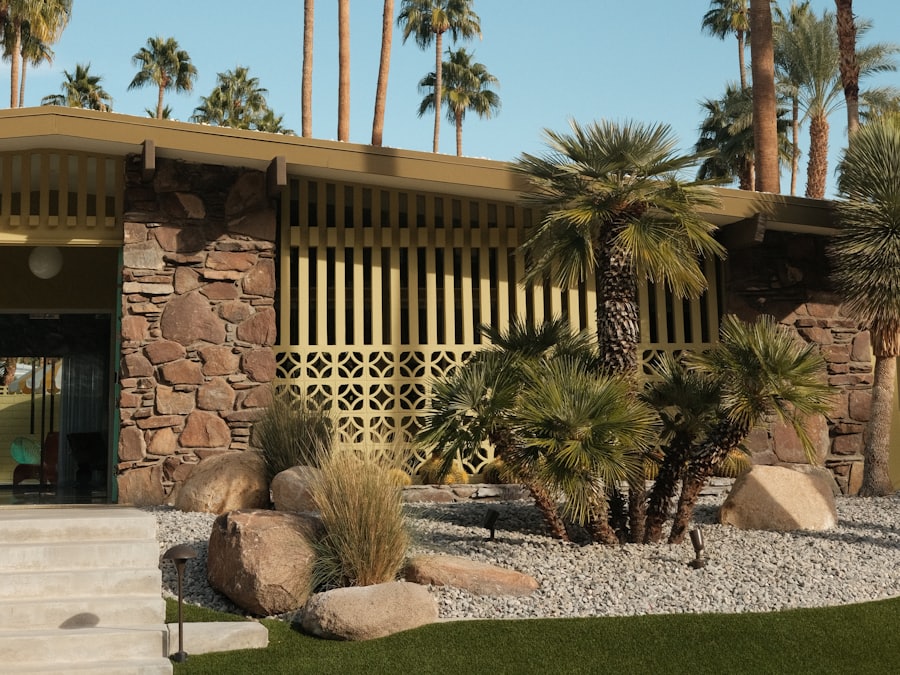 A mid-century modern desert home with stone walls and palm trees under a blue sky.