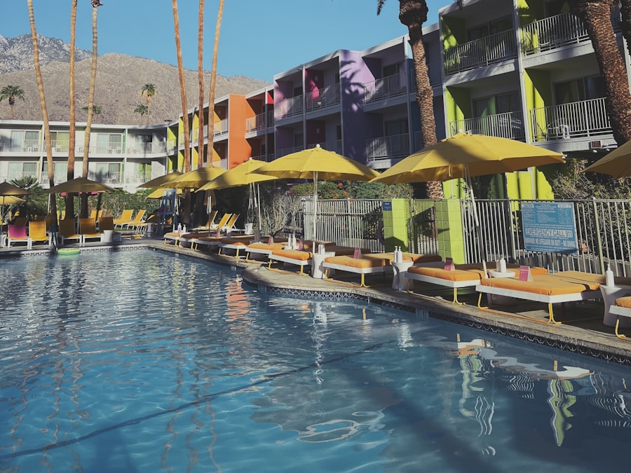 A long pool edged with loungers and yellow umbrellas beside palm trees.