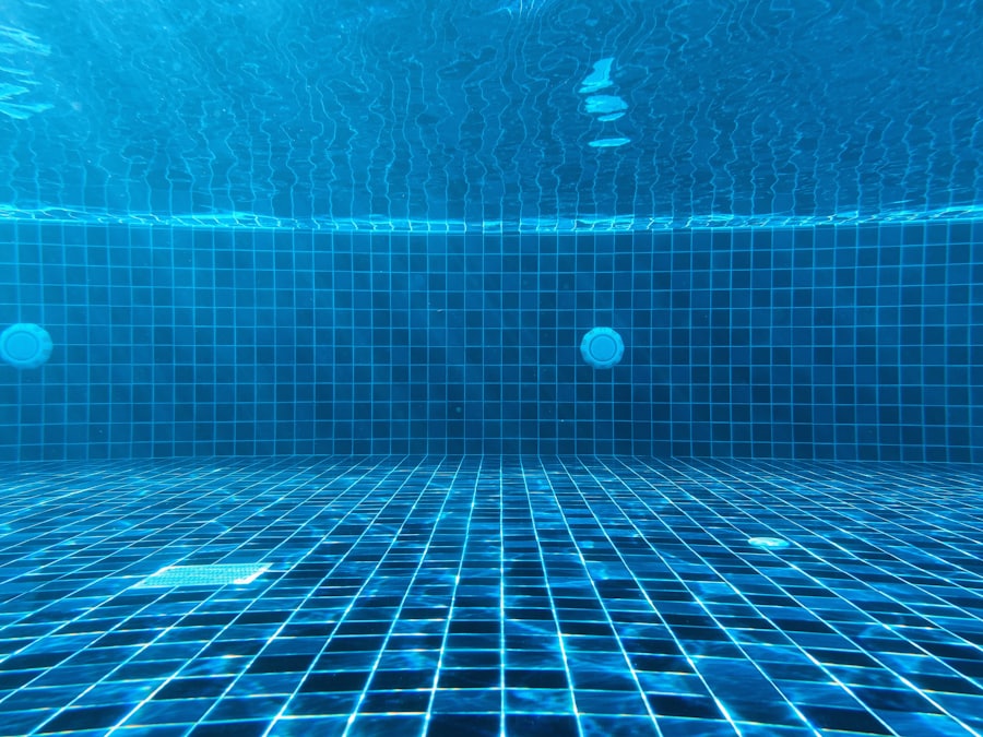 An underwater view of a blue tiled pool floor and drain.